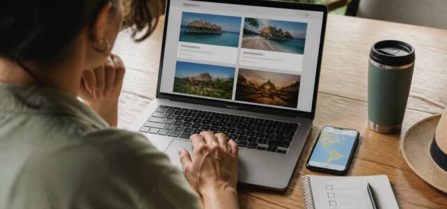 Reiziger die op een laptop vakanties vergelijkt aan een tafel met notities en een telefoon